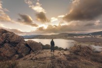 Uomo che guarda il tramonto sul lago dalla cima della collina — Foto stock
