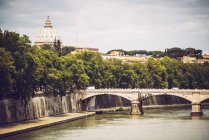 Distant view of bridge on Tiber river over  St. Peter Basilica facade — Stock Photo