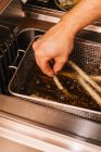 Close up view of male hand putting asparagus in frying oil — Stock Photo