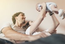Feliz jovem casal segurando recém-nascido bebê no ar — Fotografia de Stock