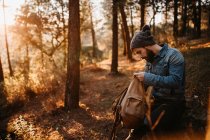 Vue latérale du touriste regardant dans le sac à dos dans la forêt d'automne . — Photo de stock