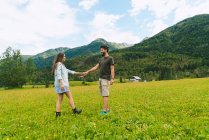 Couple holding hands on meadow in hills — Stock Photo