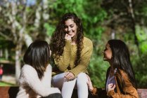 Retrato de três jovens mulheres conversando no parque — Fotografia de Stock