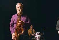 Uomo anziano che suona il sassofono sul palco — Foto stock