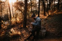 Homem sentado na floresta e olhando para a mochila — Fotografia de Stock