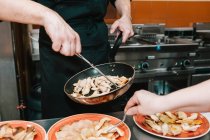 Серединна секція шеф-кухаря розміщує інгредієнти на тарілках в ресторані — стокове фото