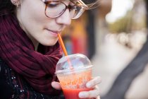 Pretty young girl having a refreshing drink in street. — Stock Photo