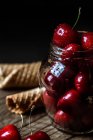 Cherries in jar and waffle cones — Stock Photo