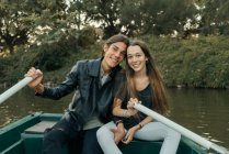 Portrait of young couple sitting in boat and looking at camera at park lake — Stock Photo