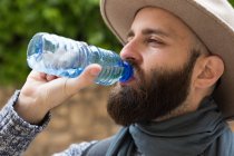 Retrato de homem barbudo usando chapéu de água potável — Fotografia de Stock
