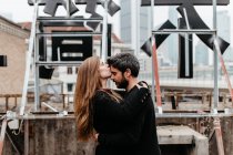 Vista lateral da menina beijando a testa do namorado no telhado — Fotografia de Stock