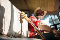 Close up view of bass guitar neck at front seat in van — Stock Photo