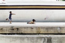 КАУЛА-ЛУМПУР, МАЛАЗИЯ - 18 апреля 2016 г.: Мальчик смеется и указывает на лежащую на земле девочку — стоковое фото