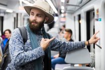 Турист у вагоні, який вказує на карту метро і дивиться з заплутаним обличчям — стокове фото