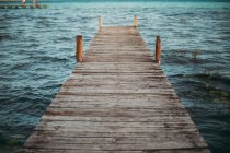 Wooden pier over turquoise ocean waves — Stock Photo