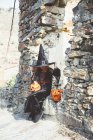 Menina no traje de Halloween sentado na parede de pedra — Fotografia de Stock