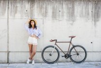 Chica posando cerca de bicicleta - foto de stock
