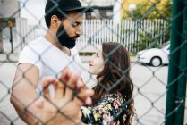 Couple posant derrière une clôture métallique — Photo de stock