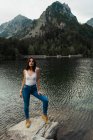 Женщина позирует на камне у горного озера — стоковое фото