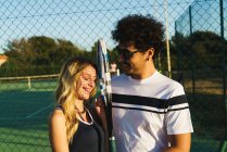 Fröhliches Paar posiert auf Tennisplatz im Sonnenuntergang — Stockfoto