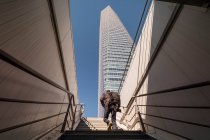 Hombre subiendo las escaleras para darse prisa rascacielos - foto de stock