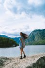 Donna in posa su pietra al lago di montagna — Foto stock
