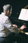 Старший чоловік в окулярах грає на піаніно — стокове фото