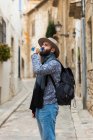 Bearded man with backpack drinking water in street. — Stock Photo