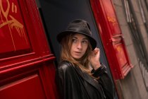 Young girl in hat looking out of doorway — Stock Photo