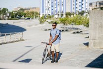 Чоловік ходить з велосипедом на вулиці — стокове фото