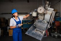 Female mechanic wearing hardhat operating a hoist to lift compressor engine — Stock Photo
