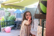 Счастливая девушка целится водяными пушками в камеру на заднем дворе — стоковое фото
