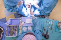 Vue du dessus des travailleurs médicaux debout au-dessus de la table avec équipement pour l'opération chirurgicale — Photo de stock