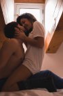 Молодая пара сидит и целуется с желанием в постели — стоковое фото