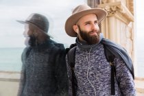 Портрет бородатого чоловіка в навушниках, що спираються на скло і дивиться в сторону — стокове фото