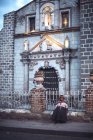 AYACUCHO, PERU - 30 DICEMBRE 2016: Vecchia donna seduta davanti alla recinzione della chiesa in strada e che guarda da parte — Foto stock