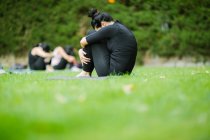 Seitenansicht einer Frau, die sich auf dem Rasen des Parks knieend umarmt — Stockfoto