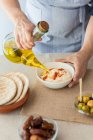 Woman pouring olive oil on hummus — Stock Photo