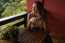 Laughing woman sitting with coffee at terrace — Stock Photo