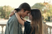 Portrait of young couple embracing face to face at park — Stock Photo