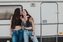 Zwei gut gelaunte Freundinnen, die sich am Anhänger umarmen und die Zunge herausstrecken — Stockfoto
