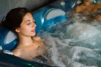 Donna rilassante nella vasca idromassaggio con gli occhi chiusi — Foto stock