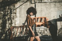 Jovem com afro vestindo saia de couro preto posando na planta de construção — Fotografia de Stock