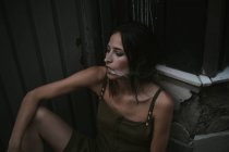 Retrato de mulher morena exalando fumaça de cigarro e olhando para longe penosamente — Fotografia de Stock