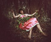 Donna vestita di rosa sdraiata tra i cespugli nella foresta . — Foto stock
