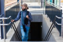 Front view of man walking up on subway station stairs and listening to music. — Stock Photo