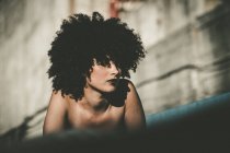 Bruna ragazza con i capelli ricci posa su parete squallida — Foto stock