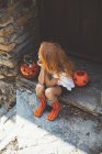 Girl sitting with pumpkin basket on porch — Stock Photo