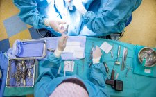 Visão superior de trabalhadores médicos em pé sobre a mesa com equipamentos para operação cirúrgica — Fotografia de Stock