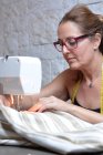Femme tailleur couture réfléchie avec la machine — Photo de stock
